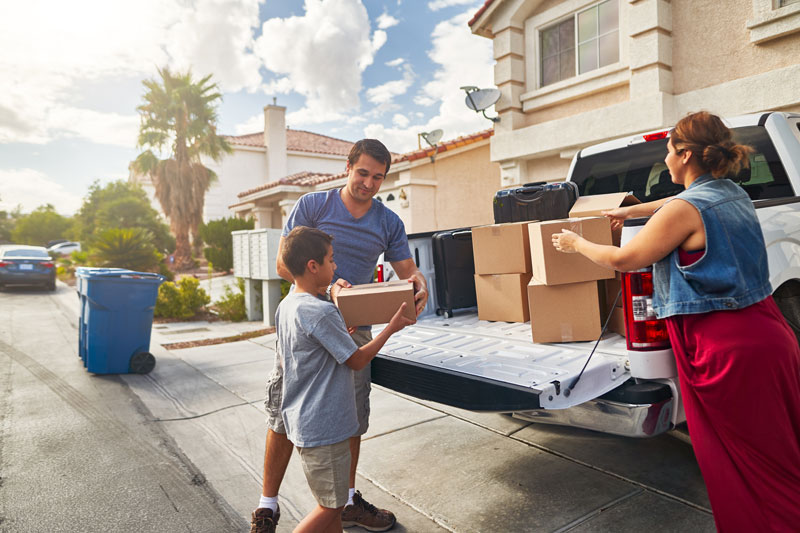 Family moving into a new home with boxes and truck, illustrating relocation from California to Nevada.